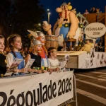 pegoulade nimes 2026 : char BD géant au crépuscule, foule et enfants
